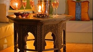 A cozy outdoor seating area with a table set for two, featuring a candle and glasses of wine. - Riad Chayma - Adults Only (Marrakech)