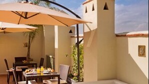 An outdoor patio with a dining table, chairs, a sofa, and a decorative tray. - Riad Chayma - Adults Only (Marrakech)