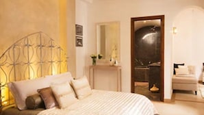 A bedroom with a bed, a nightstand, a mirror, and a door leading to a bathroom. - Riad Chayma - Adults Only (Marrakech)