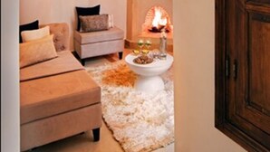 A cozy living room with a fireplace, a sofa, and a coffee table. - Riad Chayma - Adults Only (Marrakech)