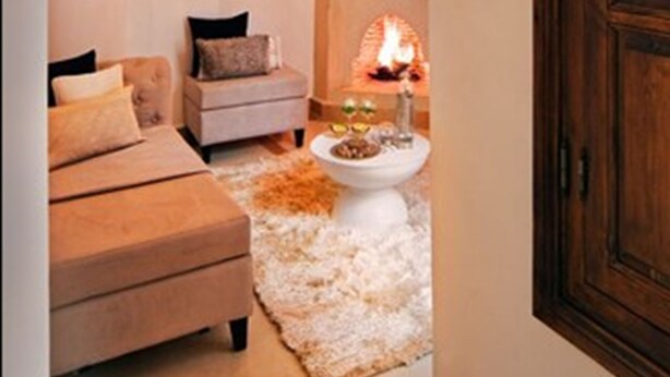 A cozy living room with a fireplace, a sofa, and a coffee table. - Riad Chayma - Adults Only (Marrakech)