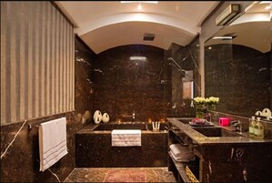 A modern bathroom with a marble sink, a bathtub, and a large mirror.