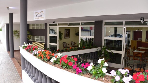 A hotel lobby with a reception desk, seating area, and a flower planter with various flowers. - Pousada Águas de Lindóia (Águas de Lindóia)