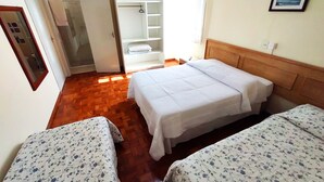 A room with two beds, a wooden floor, a white wardrobe, and a bathroom visible through an open door. - Pousada Águas de Lindóia (Águas de Lindóia)
