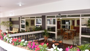 A hotel lobby with a seating area, potted plants, and a glass railing. - Pousada Águas de Lindóia (Águas de Lindóia)