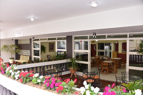 Un vestíbulo de hotel con zona de estar, plantas en macetas y barandilla de cristal.