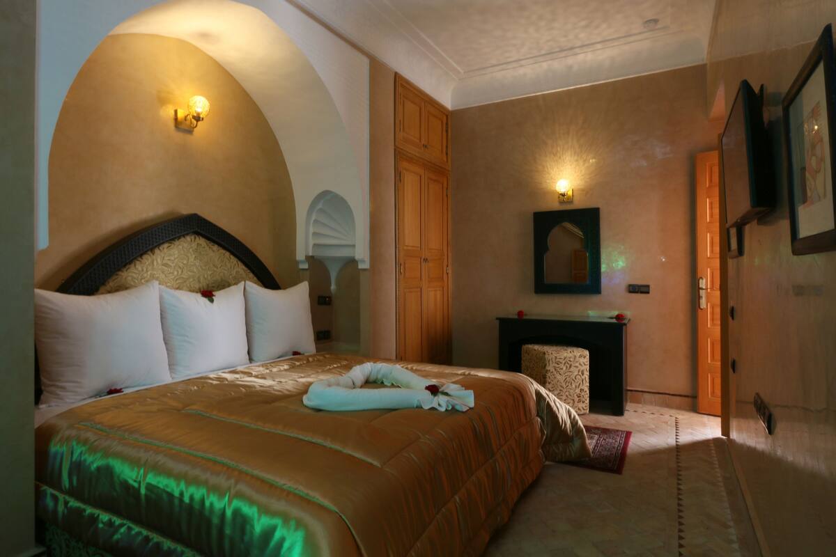 A hotel room with a large bed, a fireplace, and a wall-mounted TV.