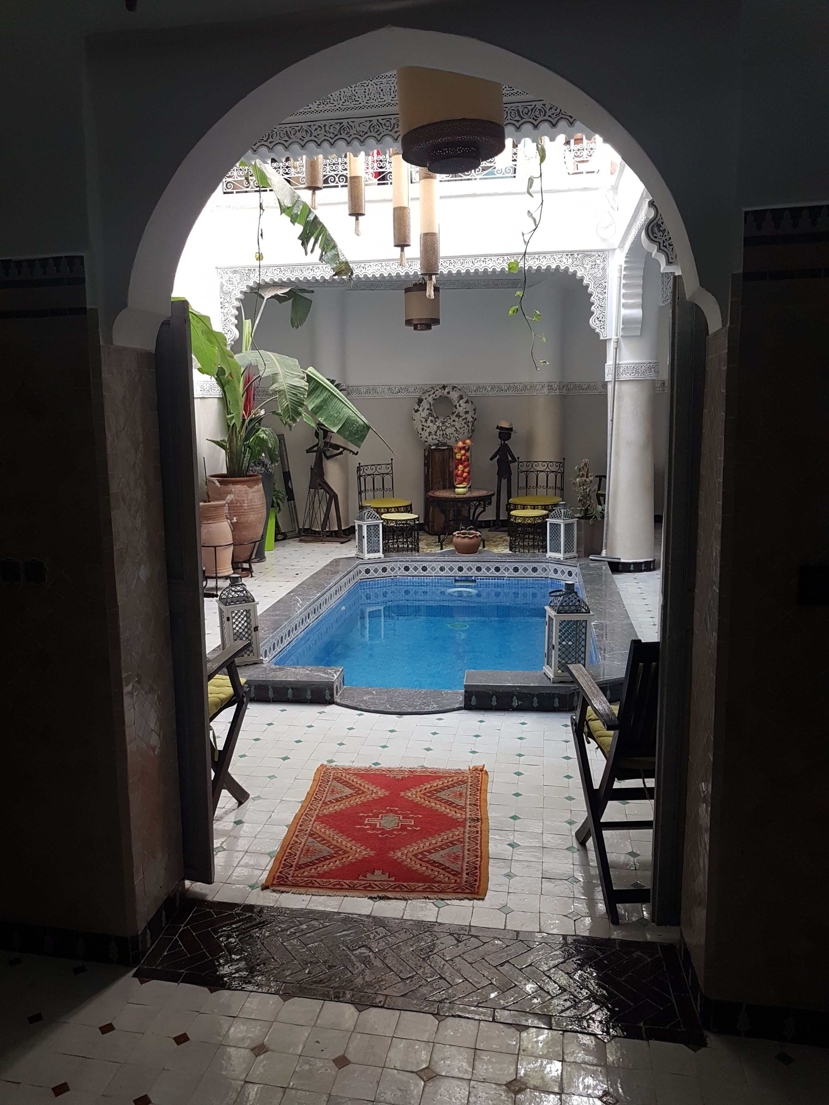 An indoor swimming pool area with a tiled floor, a red rug, and a decorative archway.