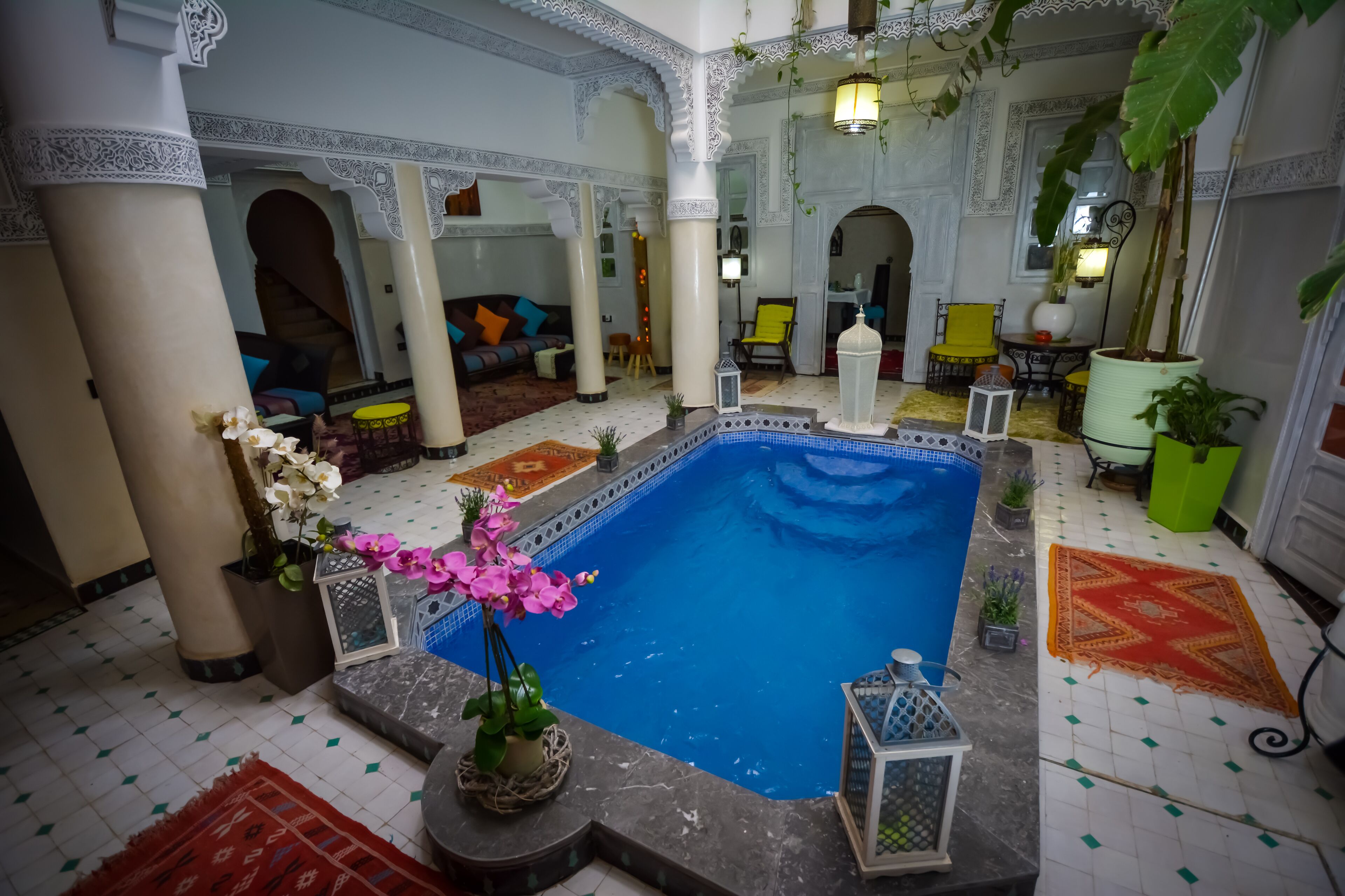 Un área de piscina interior lujosa, con suelo de baldosas, columnas decorativas y zonas de estar.
