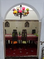 Un comedor con una mesa roja, sillas negras y una araña con luces esféricas de colores.