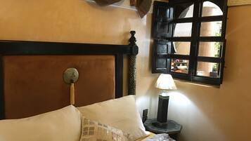 Ein Bett mit Kopfteil, eine Nachttischlampe und ein Fenster mit Ausblick.
