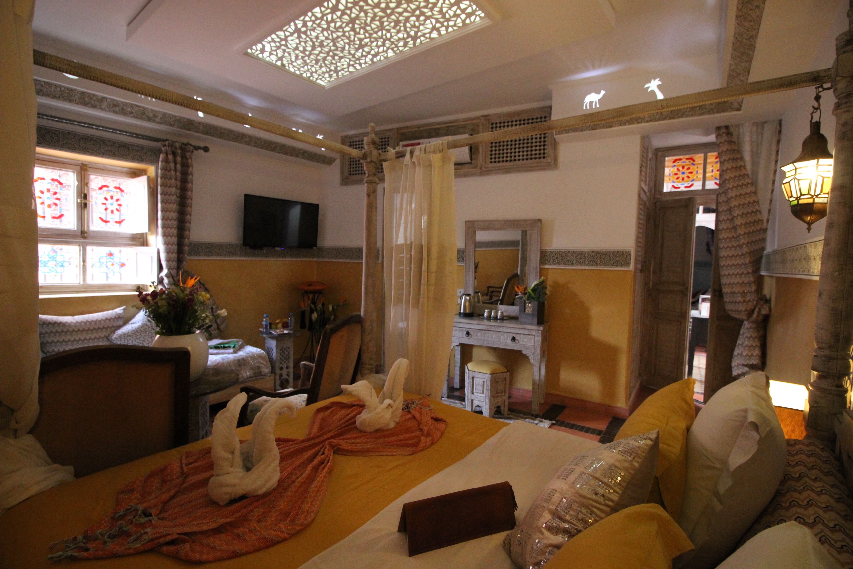 A hotel room with a bed, a desk, a television, and a window with curtains.