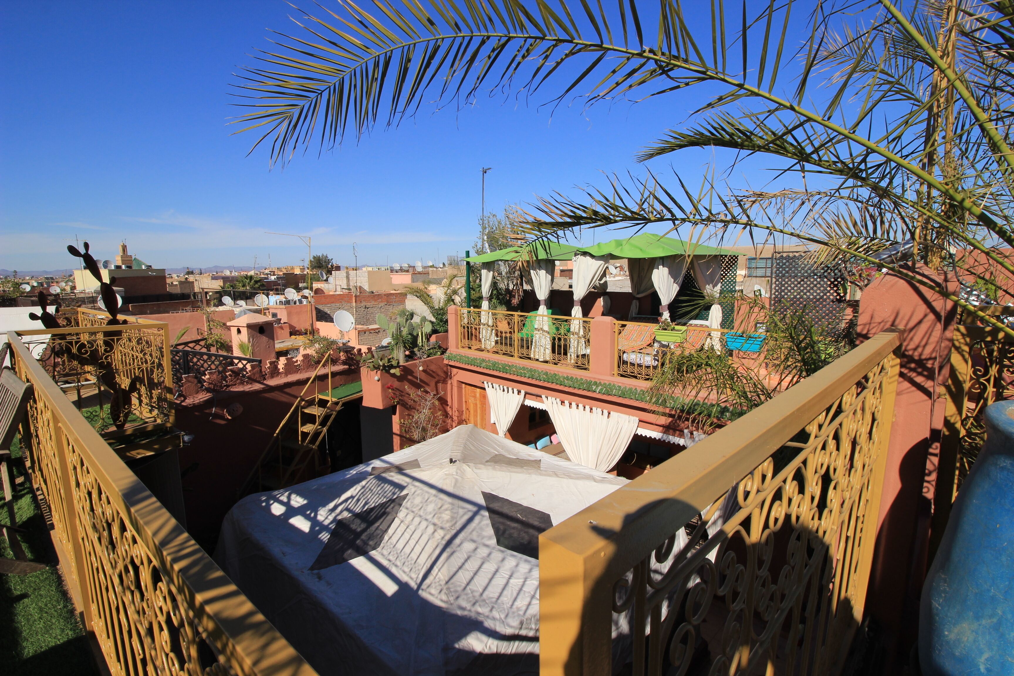 Une terrasse sur le toit offrant une vue sur le paysage urbain, avec des bâtiments et une sculpture en forme de cactus.