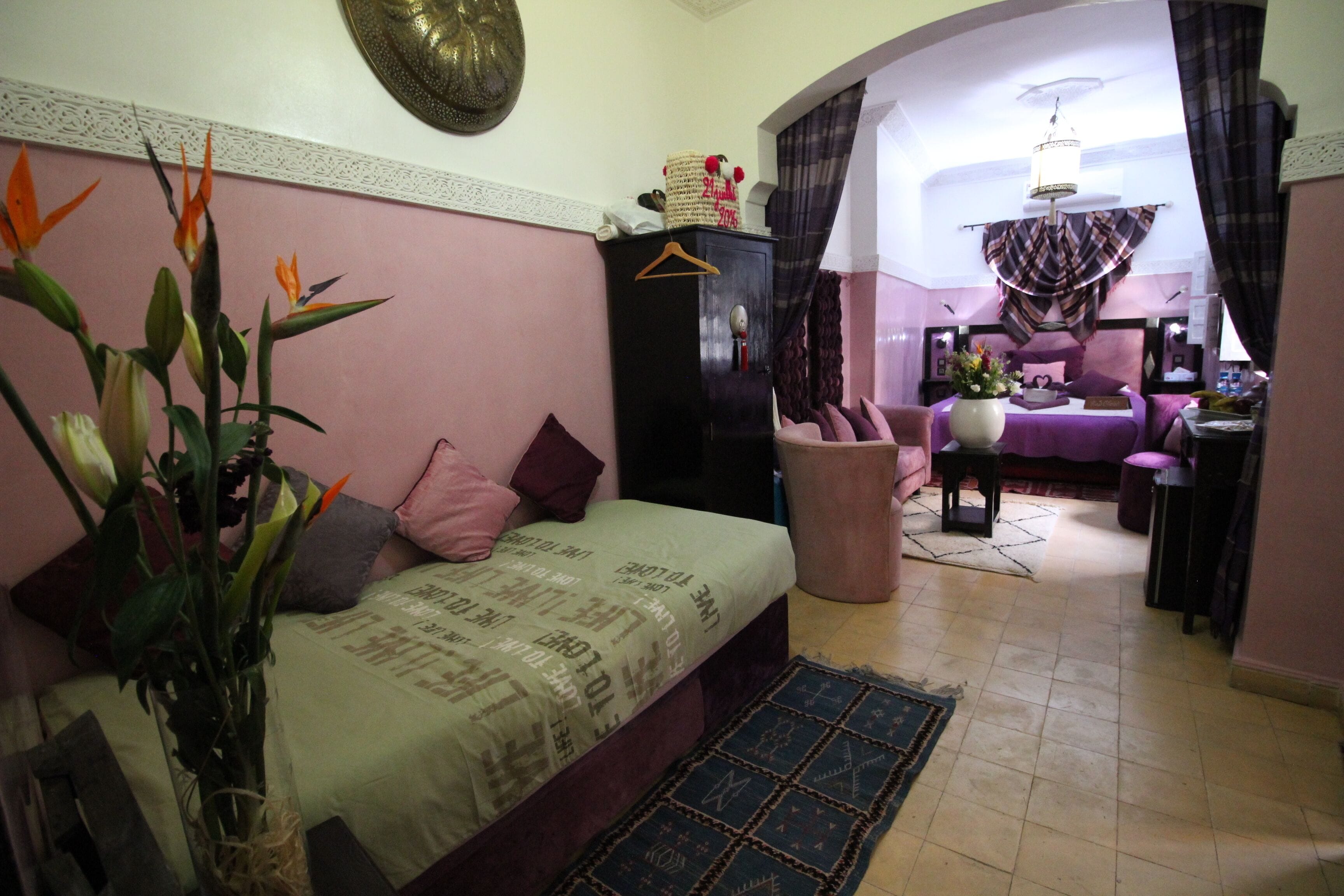 A bedroom with a bed, a dresser, a chair, and a potted plant.