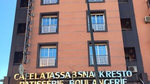 A multi-story building with a sign for 'CAFELATASSA B SNACK RESTO PATISSERIE BOULANGERIE'. - Rooms Palace (Marrakech)
