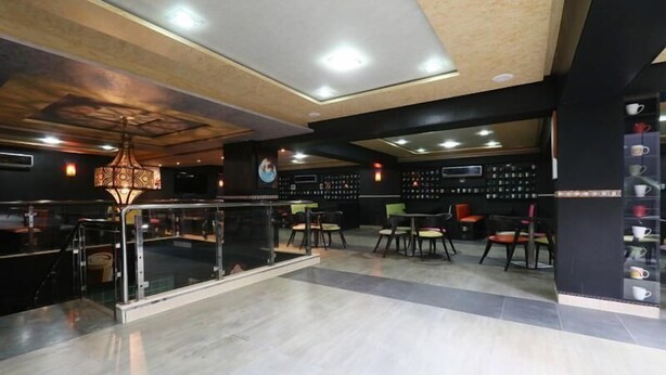 A modern cafe with a glass railing, seating area, and a coffee display. - Rooms Palace (Marrakech)