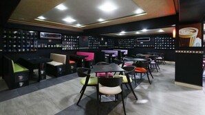 A modern cafe with multiple seating areas, including tables and booths, and a display of various items on the walls. - Rooms Palace (Marrakech)