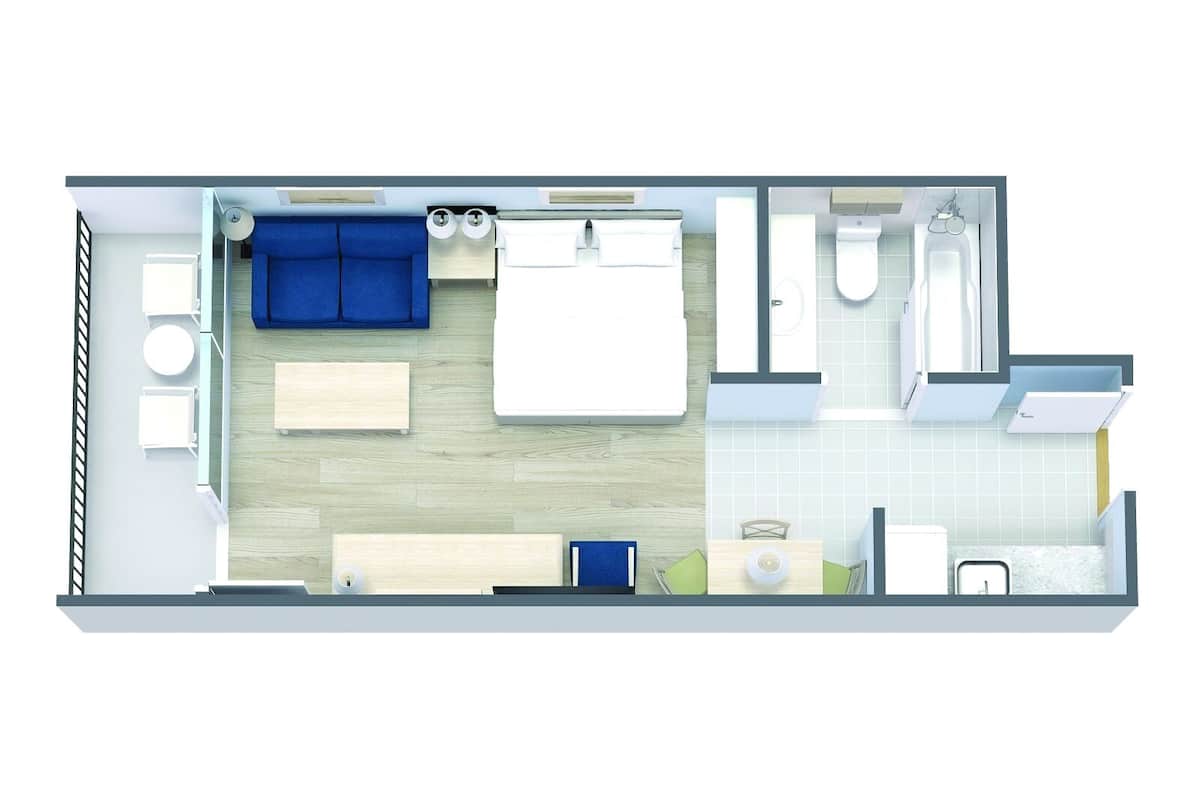A hotel room layout with a bed, a sofa, a desk, a chair, a small table, a bathroom with a toilet, sink, and shower.