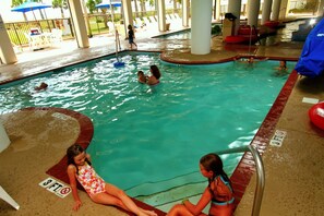 An indoor swimming pool with multiple lanes, a shallow area marked '3 FT', and a poolside area with umbrellas and lounge chairs. - Holiday Sands North On the Boardwalk (Myrtle Beach)