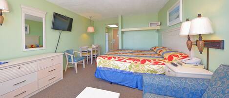 A room with a bed, a desk, a chair, a couch, and a television.