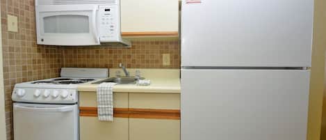 Une cuisine compacte équipée d’une cuisinière, d’un four à micro-ondes et d’un réfrigérateur.