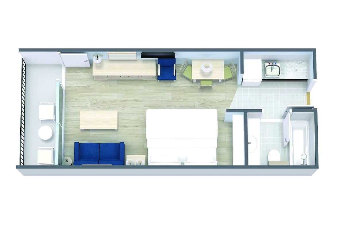 A hotel room layout with a bed, two seating areas, a small table, a sink, and a toilet.