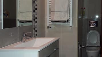 Un baño moderno con lavamanos, espejo, toallero y retrete.