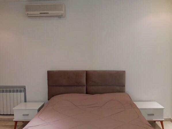Una camera da letto con un letto, due comodini, un termosifone e un condizionatore.