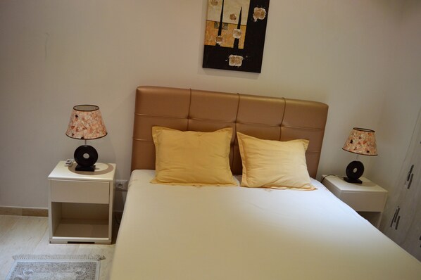A bedroom with a large bed, two bedside tables, and two lamps. - Ryma Appart (La Soukra)