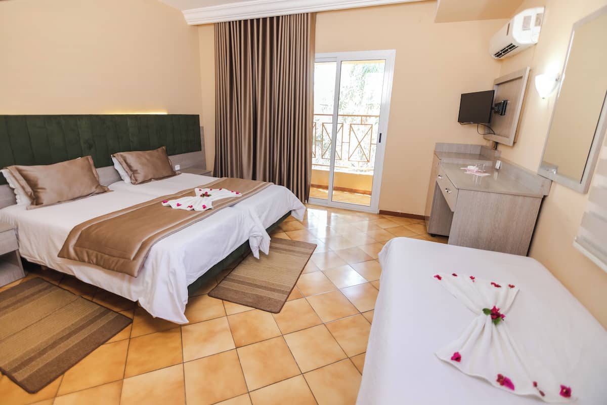 A hotel room with two beds, a balcony, a TV, and a minibar.