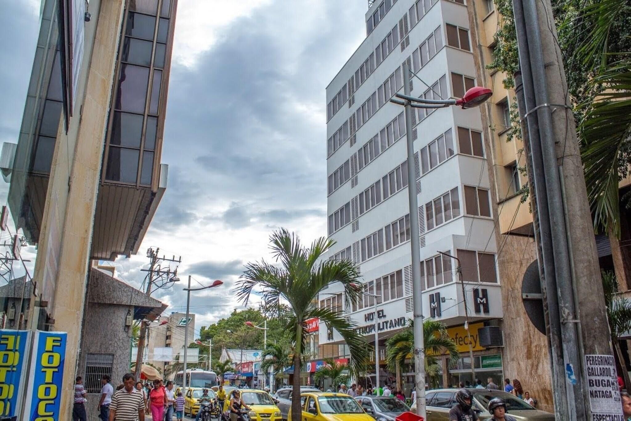 A busy urban street with multi-story buildings, including a hotel with a sign that reads 'HOTEL EL GALLARDO.'