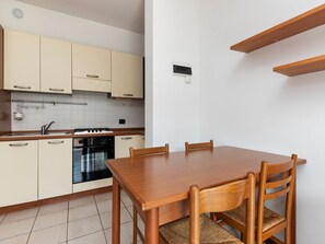A modern kitchen with a dining table and chairs, a stove, oven, and a sink.