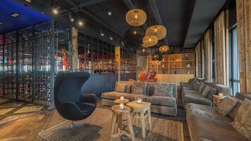 A modern lounge area with a curved black chair, a sofa set, and a wooden coffee table.