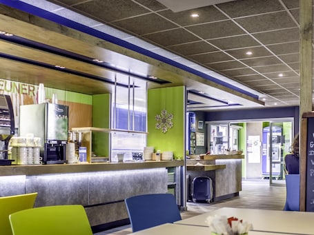 A modern hotel lobby with a bar area, seating, and a visible luggage storage.