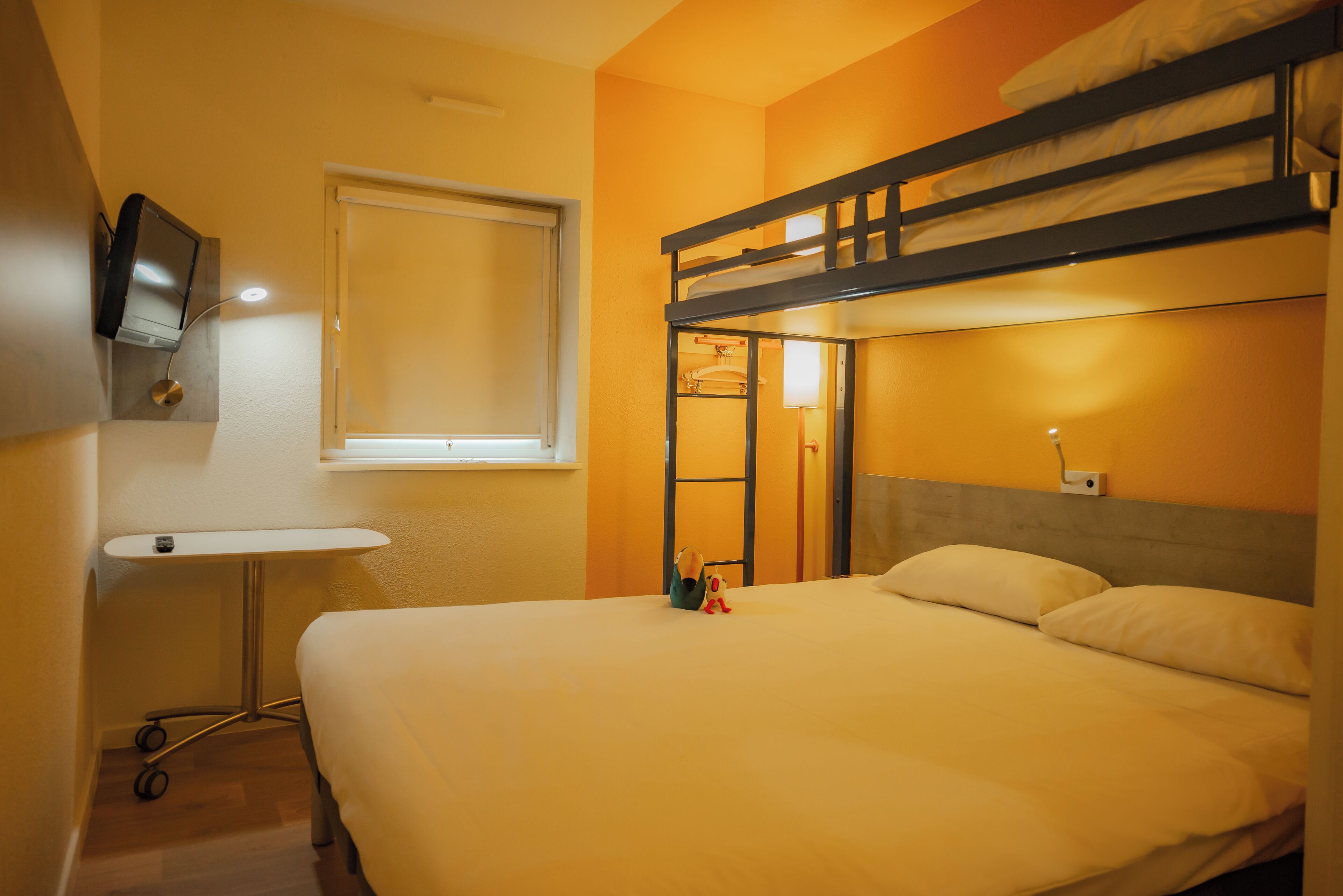 Een slaapkamer met een stapelbed, een klein bureau en een televisie.