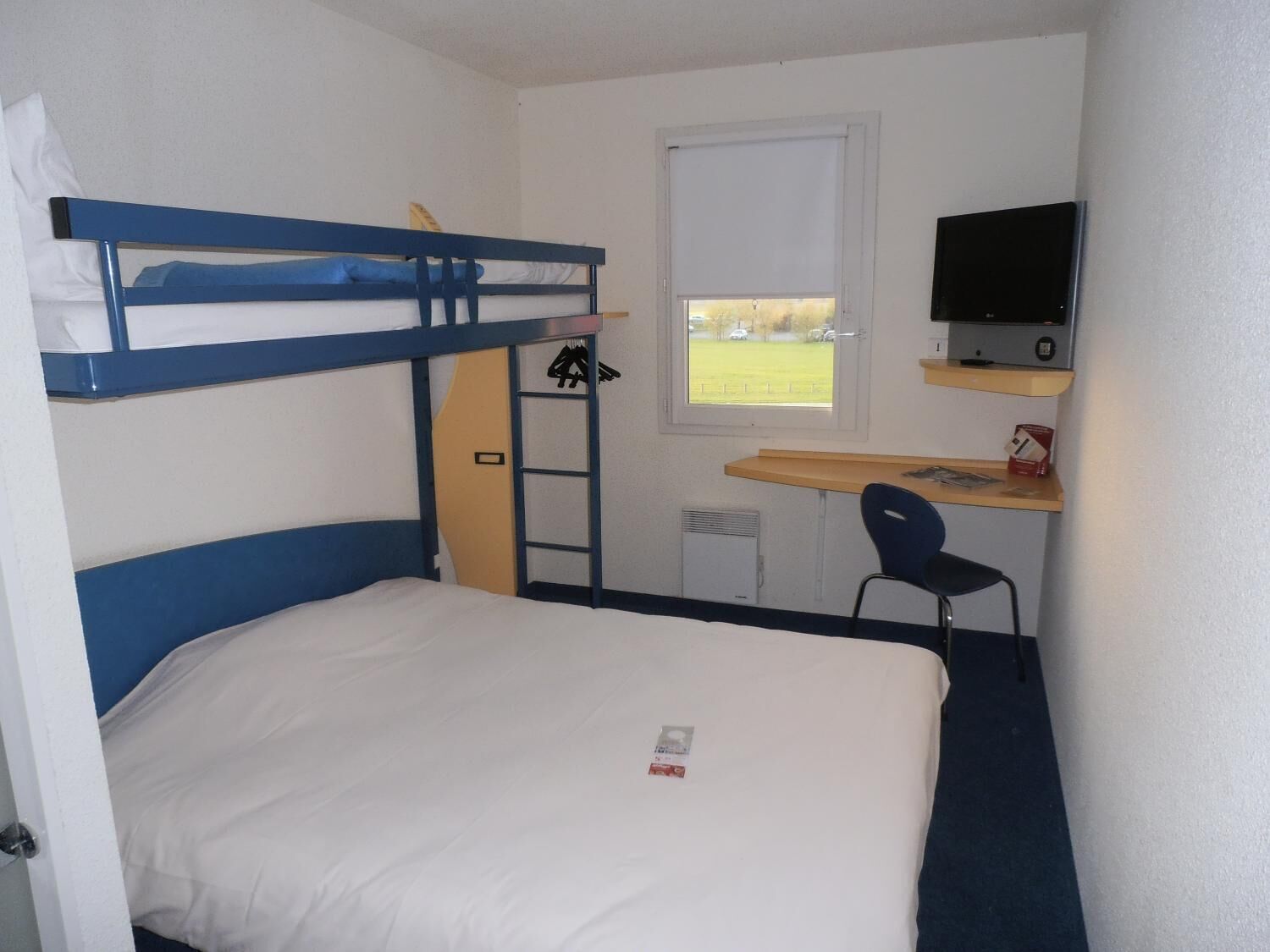 Une chambre avec un lit superposé, un bureau, une chaise et un téléviseur.