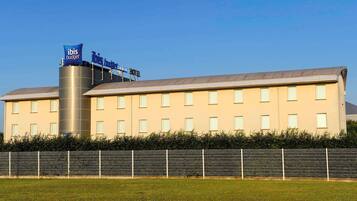 A hotel with a modern design, featuring a prominent cylindrical water tank and a sign indicating it is an ibis budget hotel.
