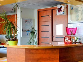Un comptoir d’accueil avec un revêtement en bois, une plante en pot, une affiche et une carte accrochée au mur.