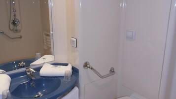 Un baño con lavamanos azul, inodoro blanco y ducha con cabezal de ducha manual.
