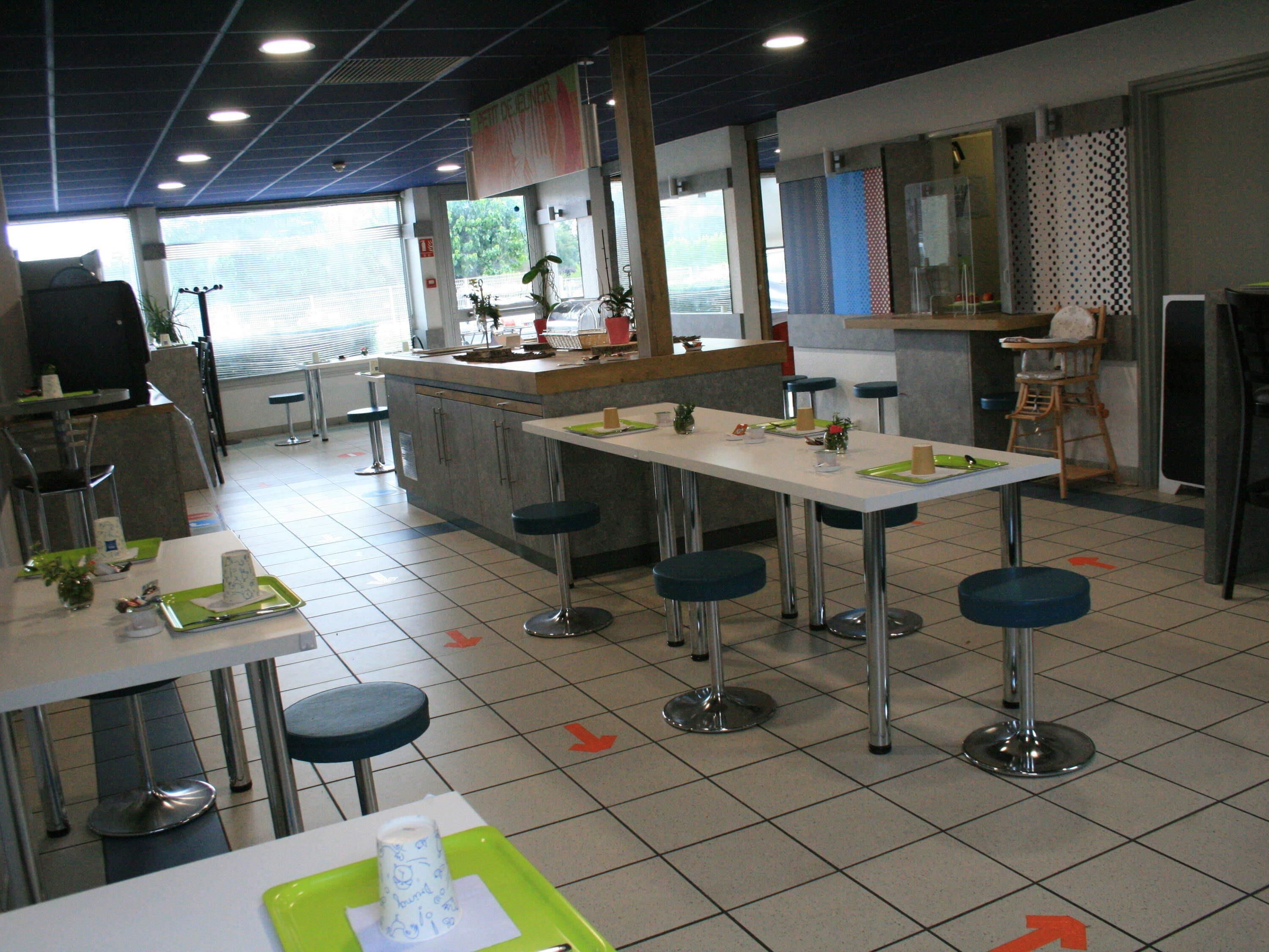 A restaurant with high tables and stools, a counter, and a view of the outdoors.