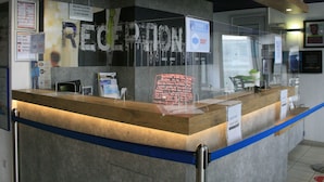 Un mostrador de recepción con un separador de vidrio y un cartel que dice 'RECEPTION', con una señal de 'STOP' encima.