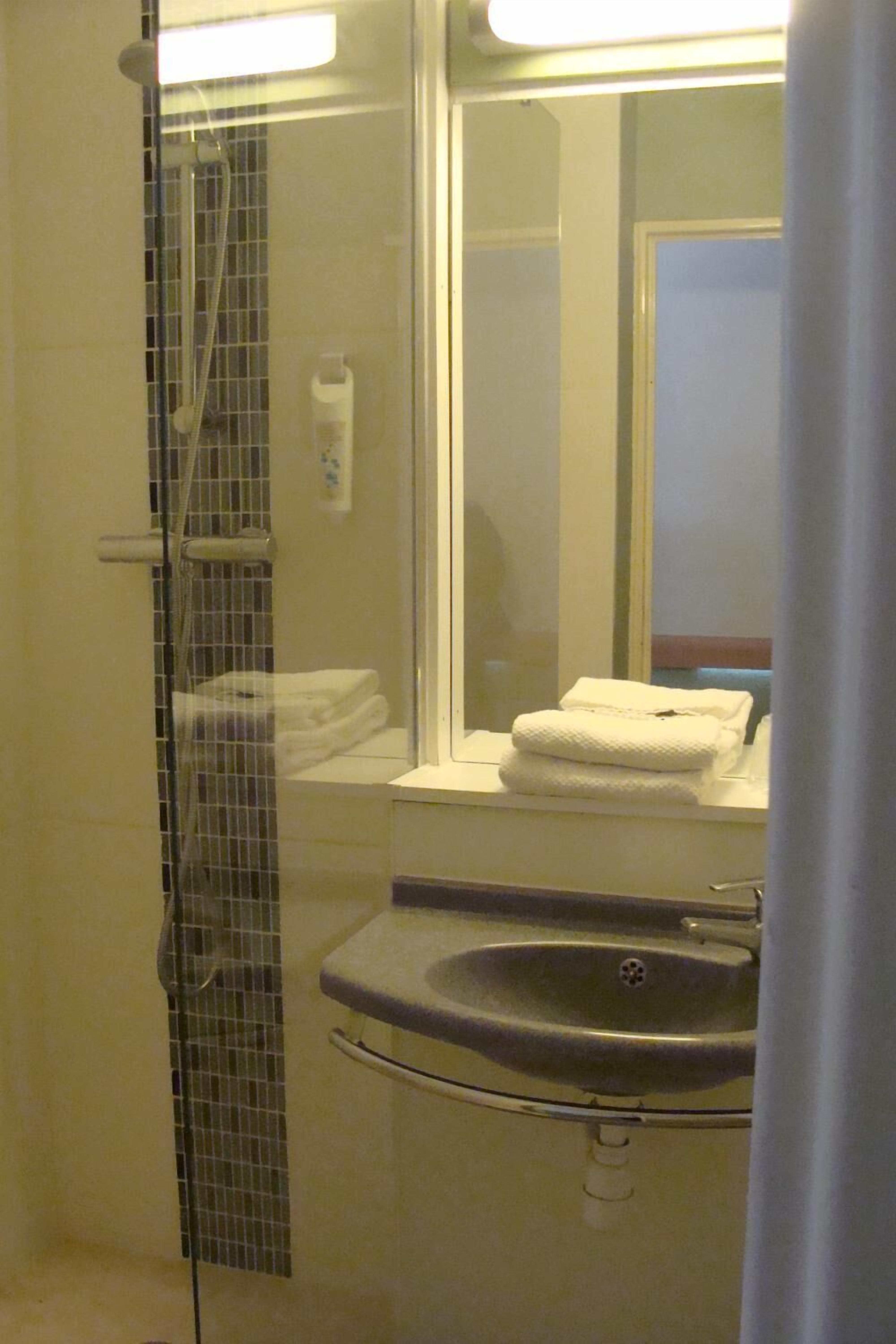 Ein Badezimmer mit Duschkabine, Waschbecken und Spiegel.