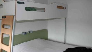 Een stapelbed met een groen hoofdeinde, een witte matras en een zwart jack op het onderste bed.