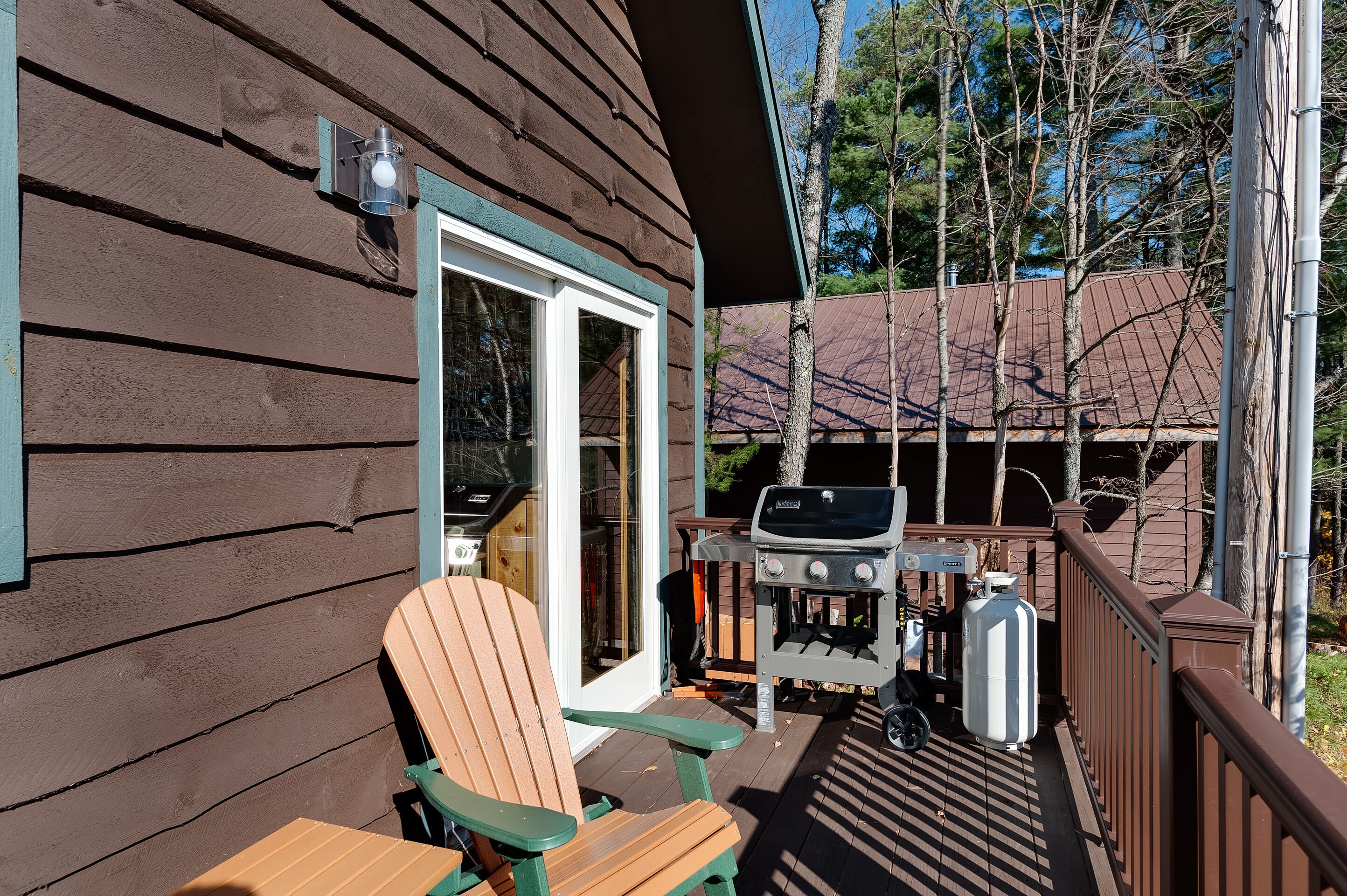 A wooden deck with a grill, a chair, and a table.
