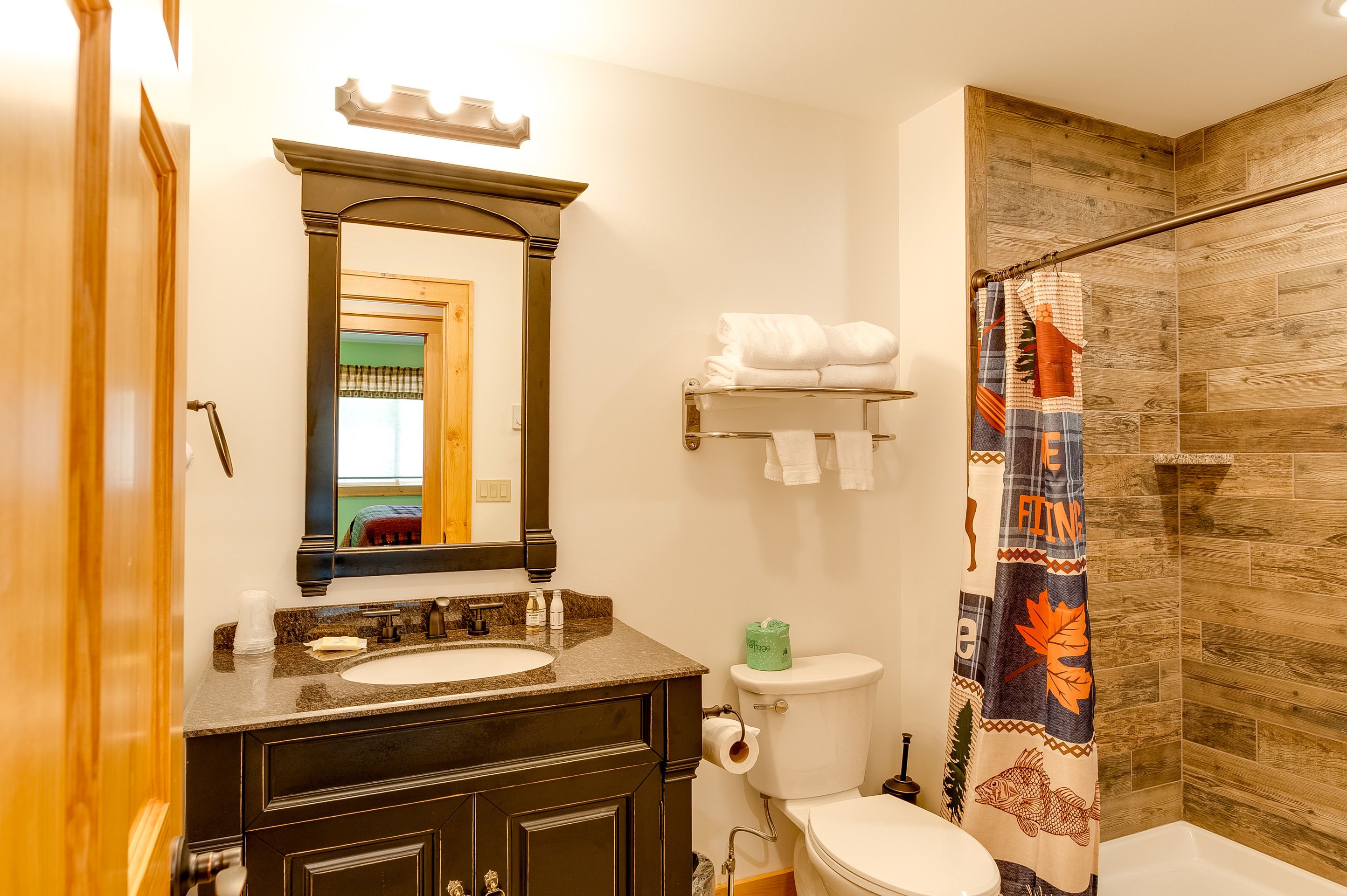 Un bagno con cabina doccia in legno, un lavandino con specchio e un water.