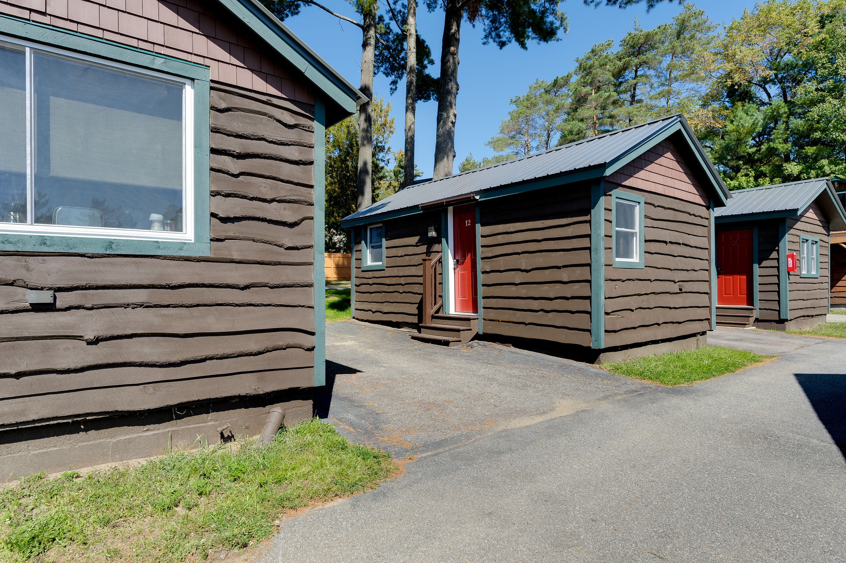 A row of log cabins with a red door, a window, and a small porch.