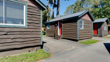 A row of log cabins with a red door, a window, and a small porch.