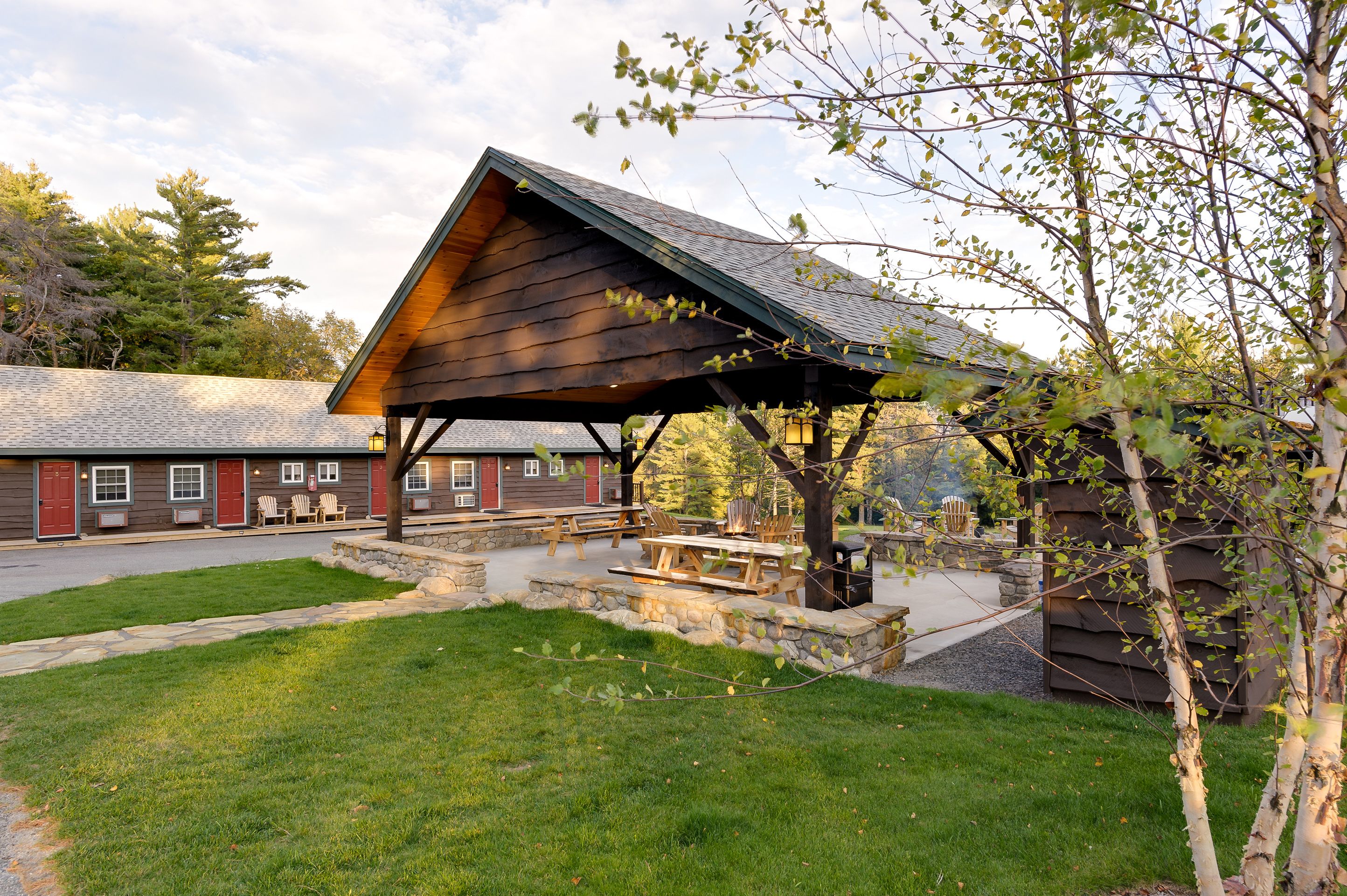 A rustic lodge with a covered picnic area, stone steps, and a stone wall.