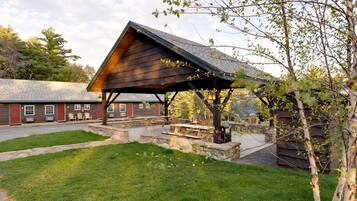 A rustic lodge with a covered picnic area, stone steps, and a stone wall.