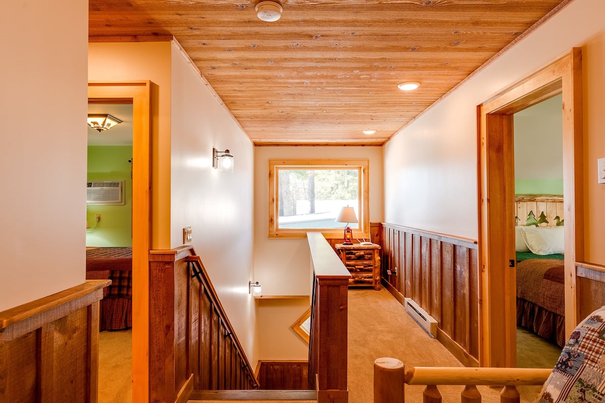 A wooden staircase with a handrail, a window with a view of the outdoors, and a small table with a lamp.